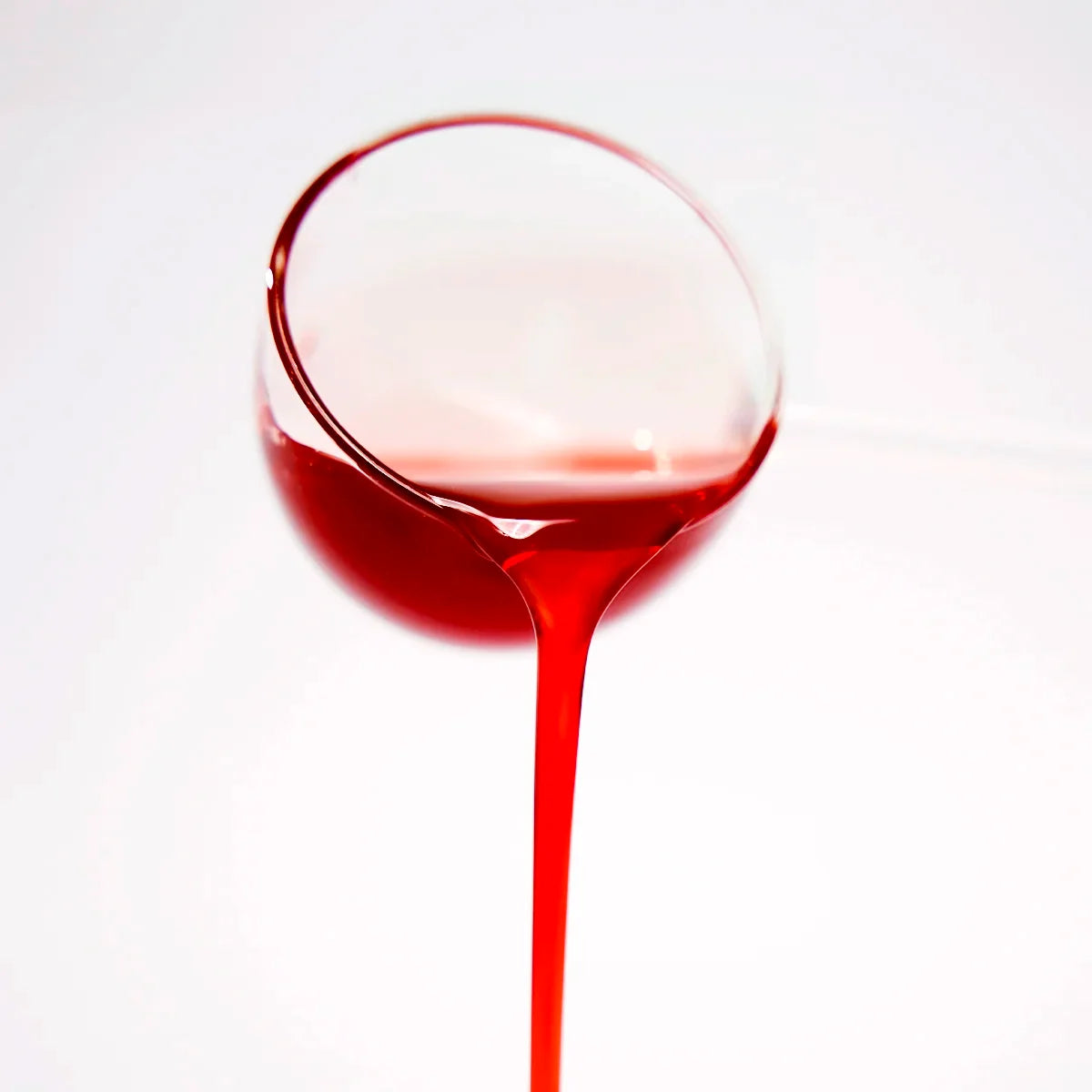 Close-up of rose syrup being poured, showcasing its ruby-red color and rich consistency.