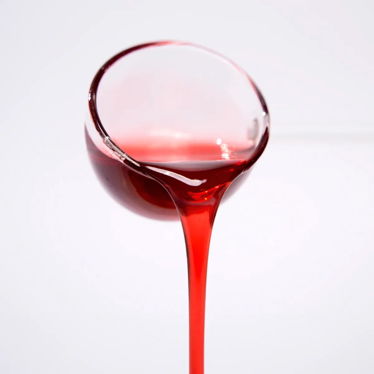 Close-up of professional hibiscus concentrated syrup pouring, showing deep ruby red color and viscous texture for bubble tea and cocktails.